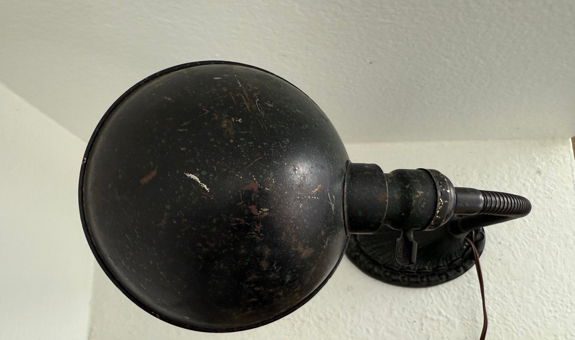 Black metal lamp with round shade on a white wall