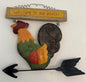 Decorative wall art of a rooster with 'Welcome to our Roost!' sign on a white wall.