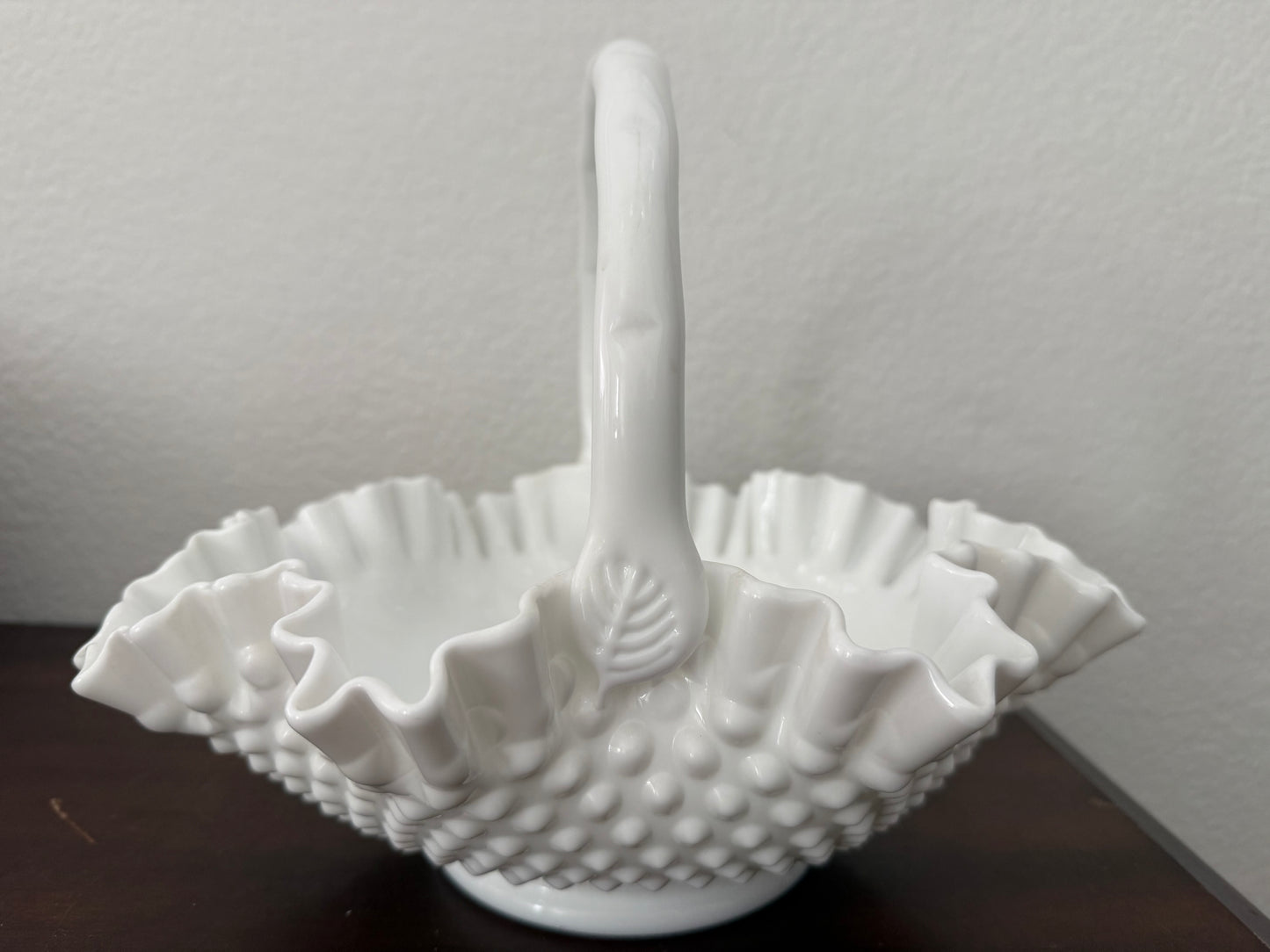 White textured ceramic basket with handle on a dark surface