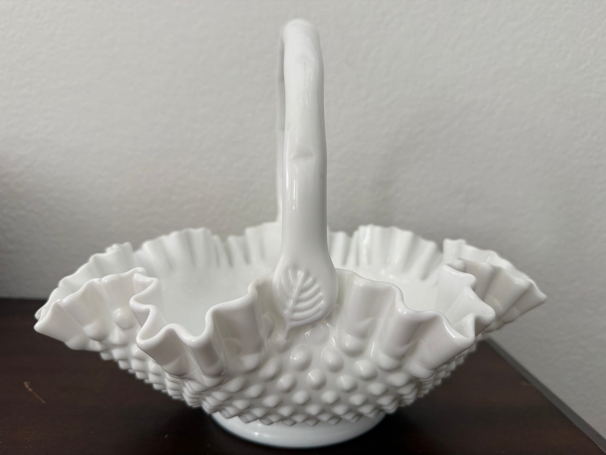 White textured ceramic basket with handle on a dark surface