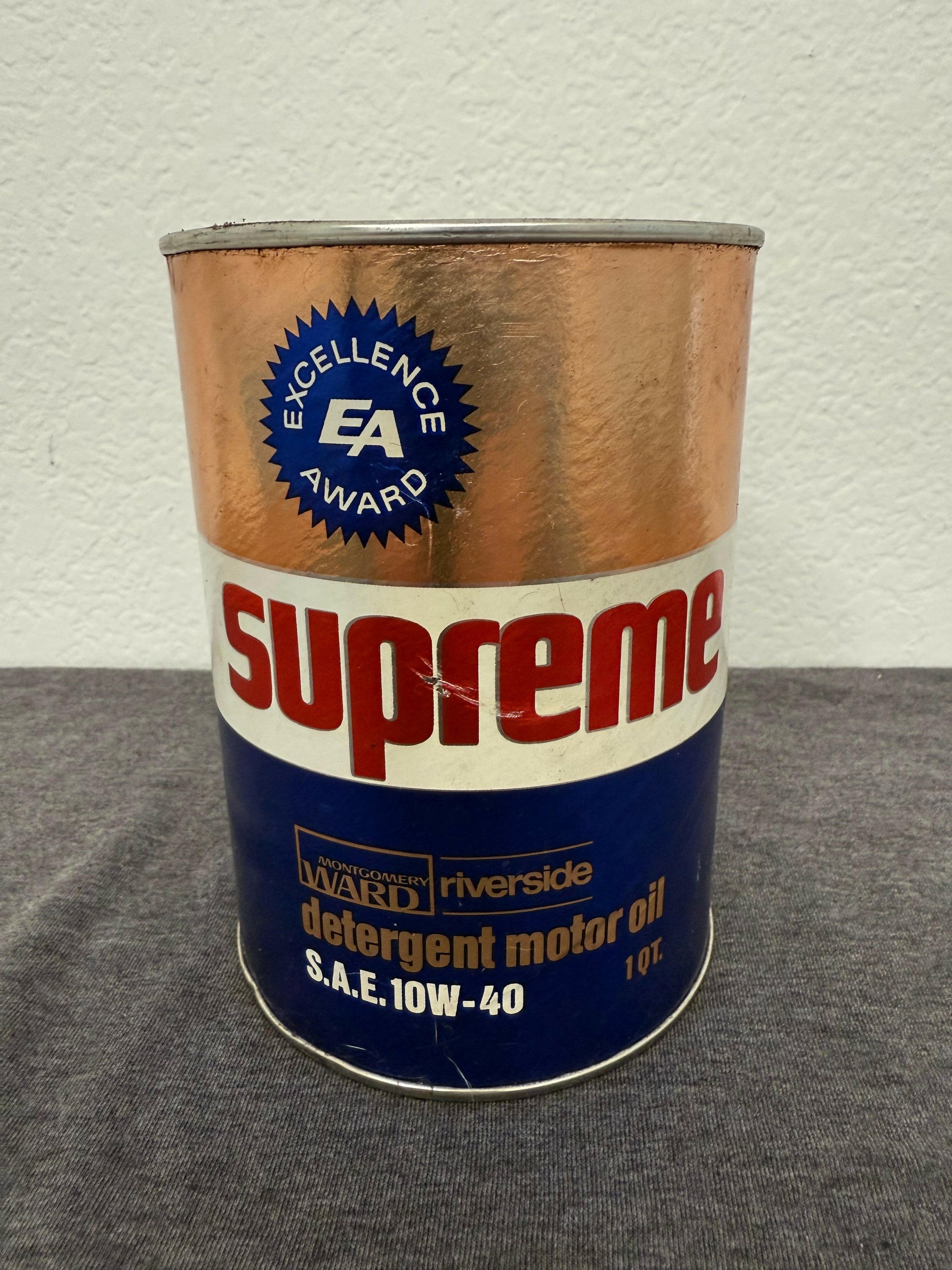 Can of Supreme brand motor oil with Excellence Award logo on a gray and white background