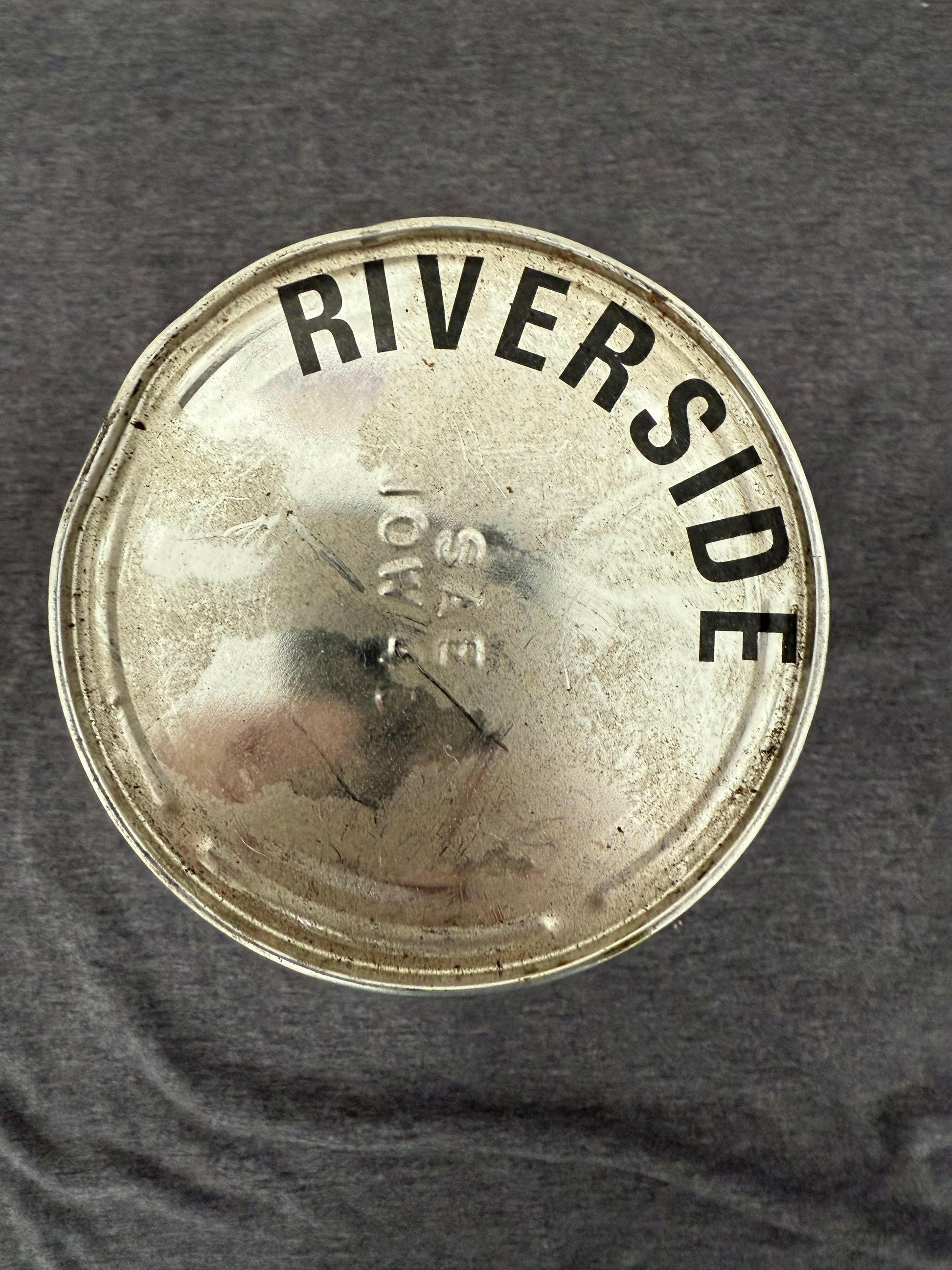 Metallic cap with 'Riverside' branding on a textured surface