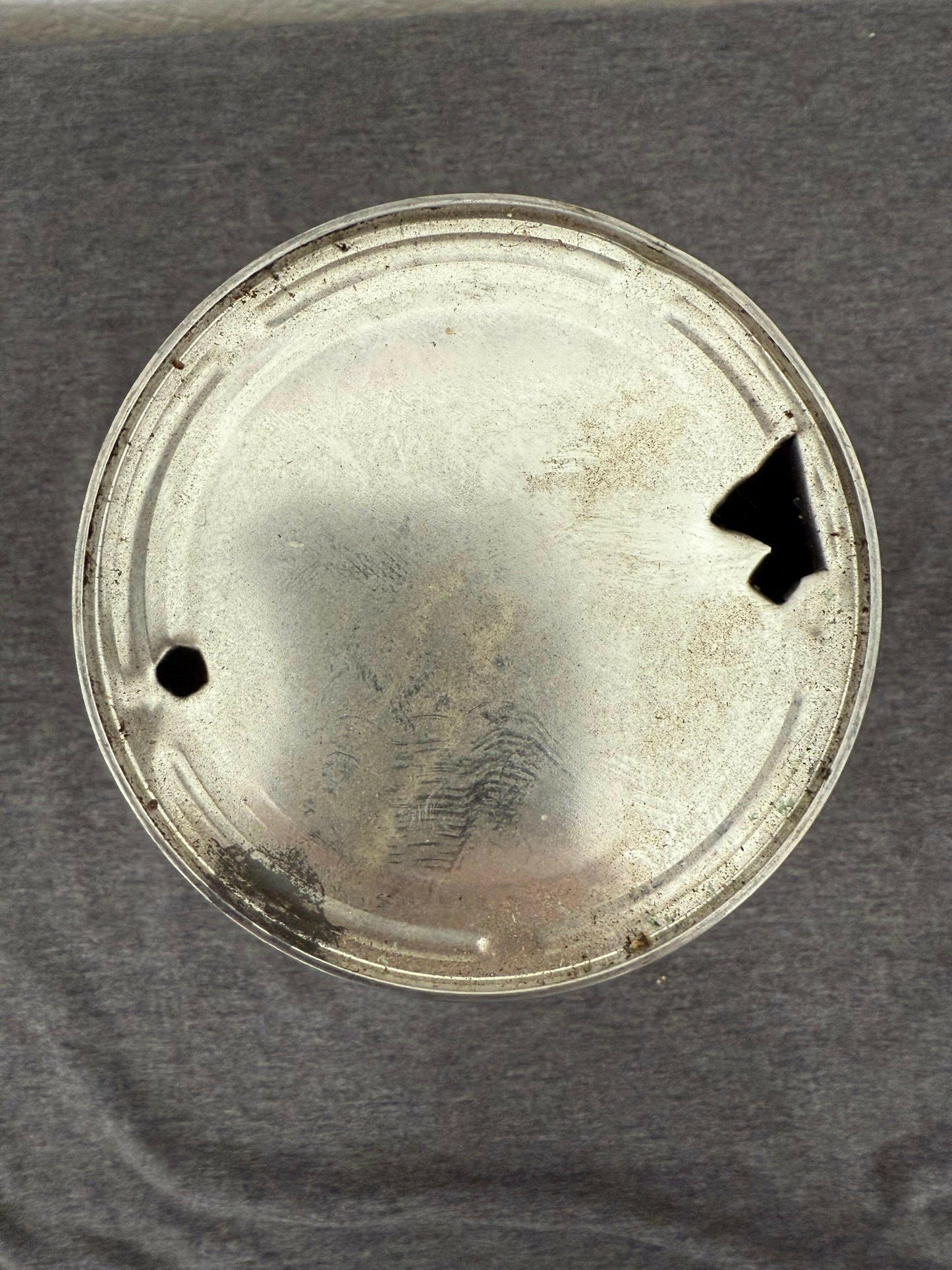 Round metallic object with a central hole on a gray background
