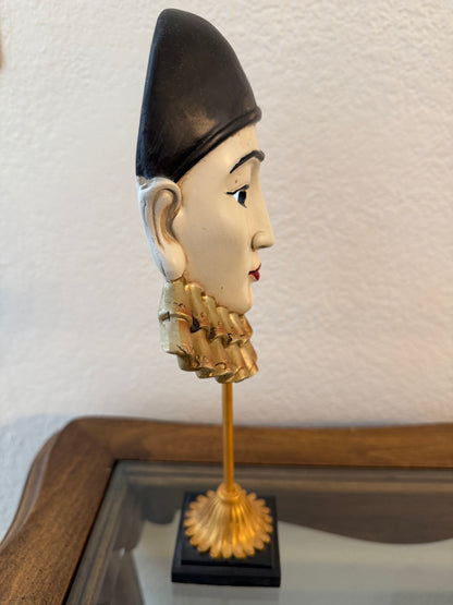 Decorative piece with a face design and gold accents on a white wall.