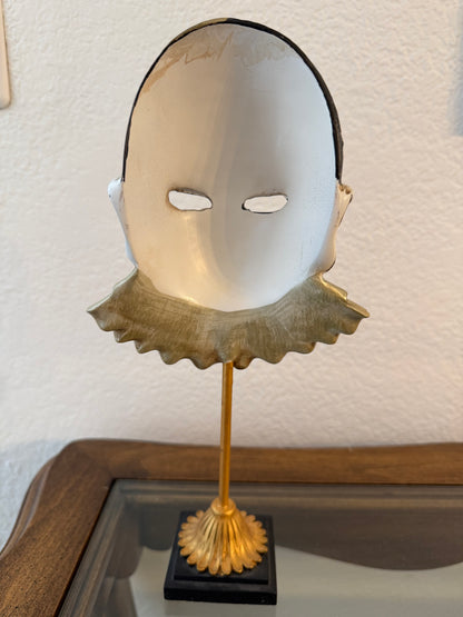 Decorative mask with a gold finish on a textured wall.