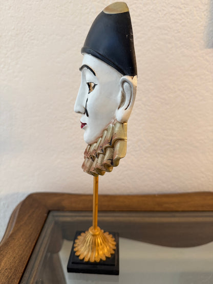 Decorative object resembling a hand holding a black object on a textured surface.