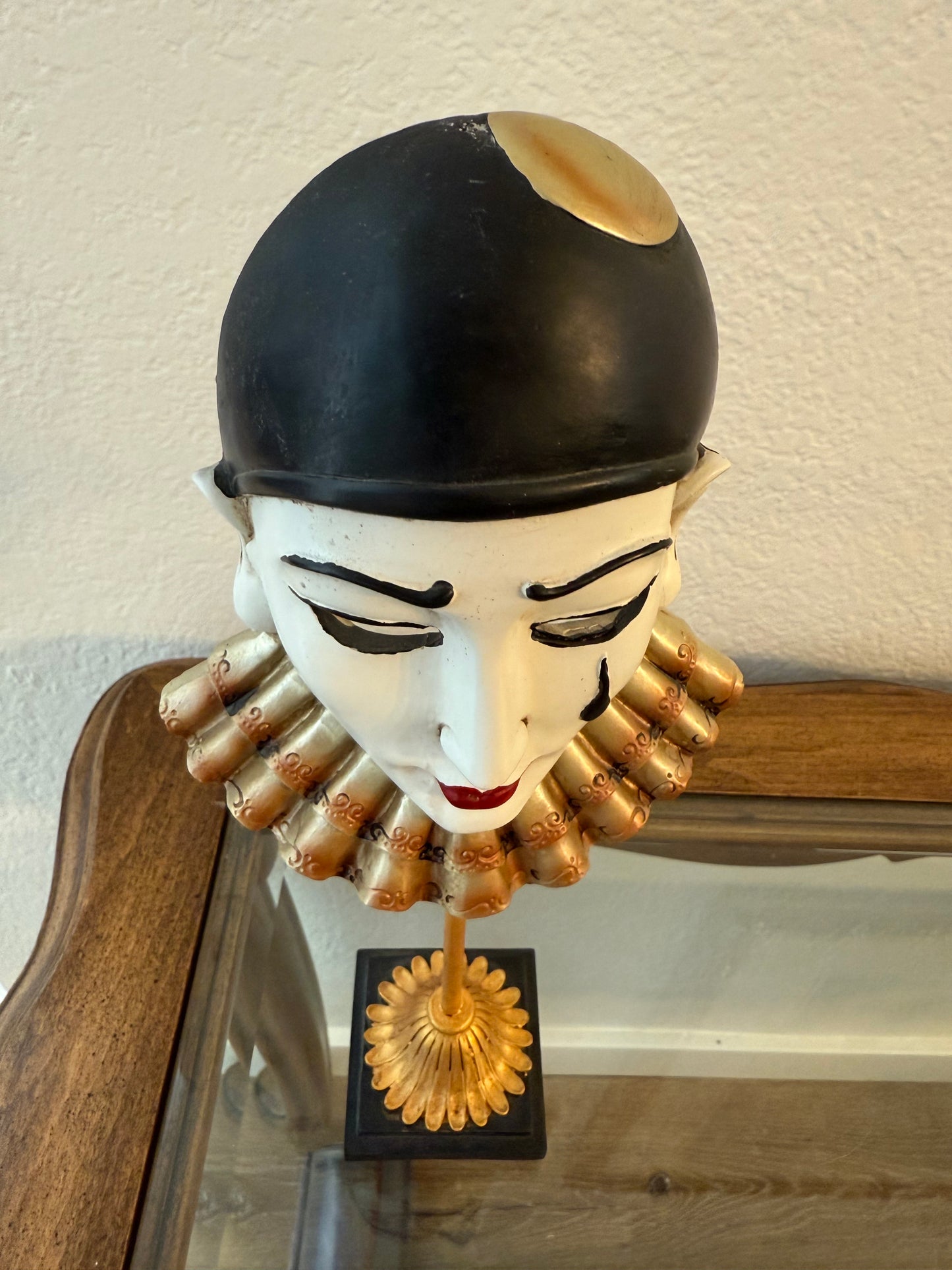 Decorative item resembling a head with gold accents on a wooden surface.