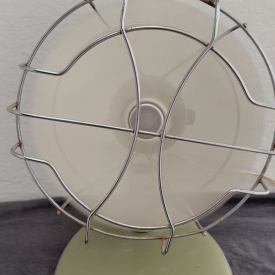 Vintage-style desk fan with white blades and metal frame against a neutral background