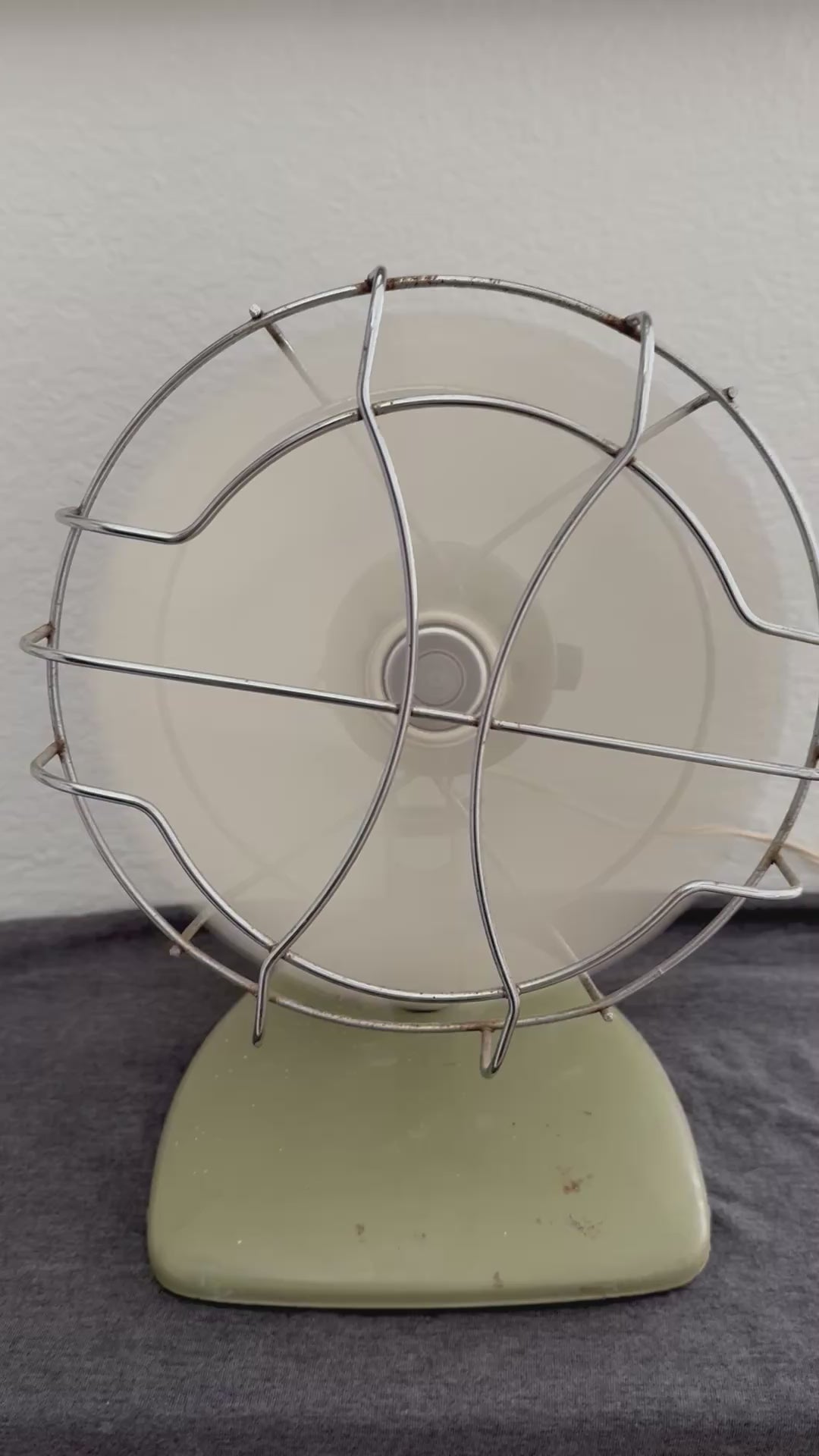 Vintage-style desk fan with white blades and metal frame against a neutral background